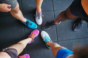 high angle of a group of sporty peoples feet wearing running shoes standing together in a huddle on a gym floor