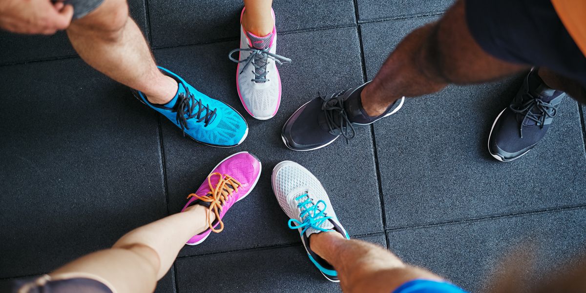 high angle of a group of sporty peoples feet wearing running shoes standing together in a huddle on a gym floor