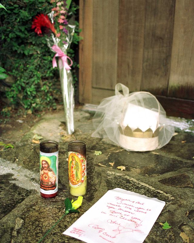flowers, two candles, a note and a gift basket sit in front of a door