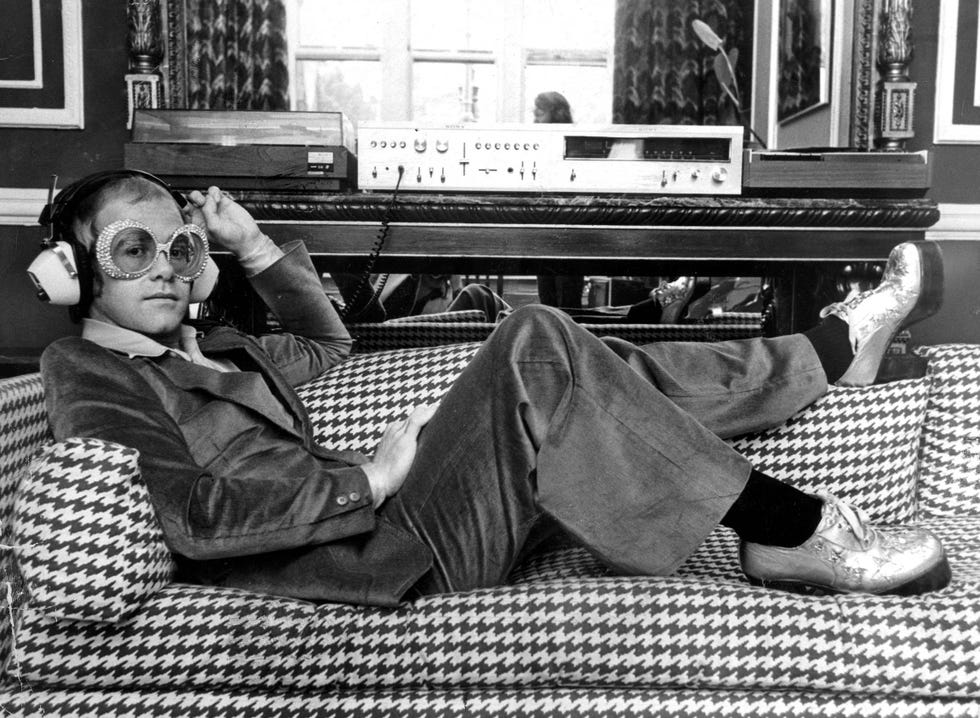 elton john escucha música tumbado en un sofá