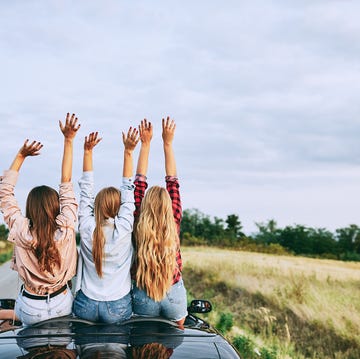 Girlfriends driving on a cabriolet vehicle.