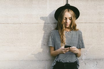 Portrait of fashionable young woman wearing hat using smartphone