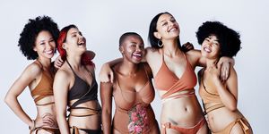 studio shot of a group of beautiful young women in posing together in swimwear against a gray background