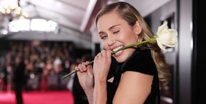 Miley cyrus eating a rose on the red carpet