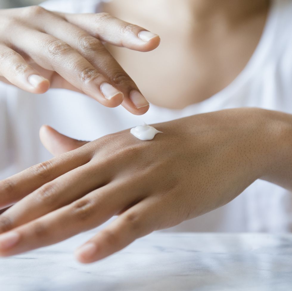 African American woman applying lotion to hand