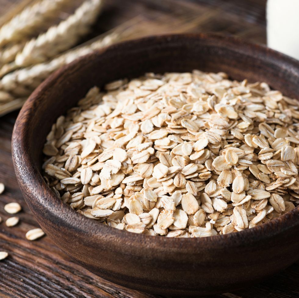 Rolled oats in wooden bowl on old wooden table