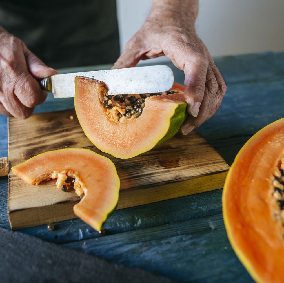 Hands of senior man cutting papaya