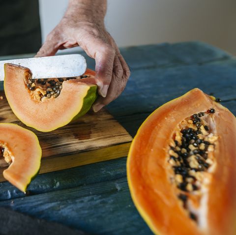 Hands of senior man cutting papaya