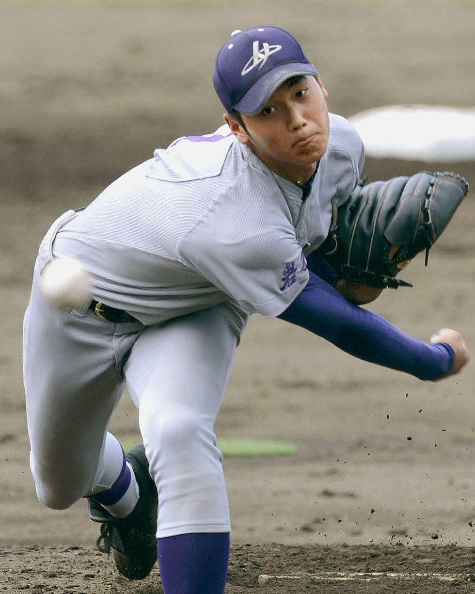 file photo taken july 26, 2012, shows shohei ohtani pitching at a high school baseball tournament in morioka, japan, he is wearing a gray uniform with purple accents, purple hat, and a black baseball glove, a blurry baseball appears in front of him as it approaches the camera