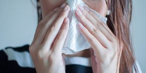 a woman is holding a tissue paper due to infectious disease