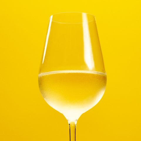 Close-Up Of White Wine Against Yellow Background