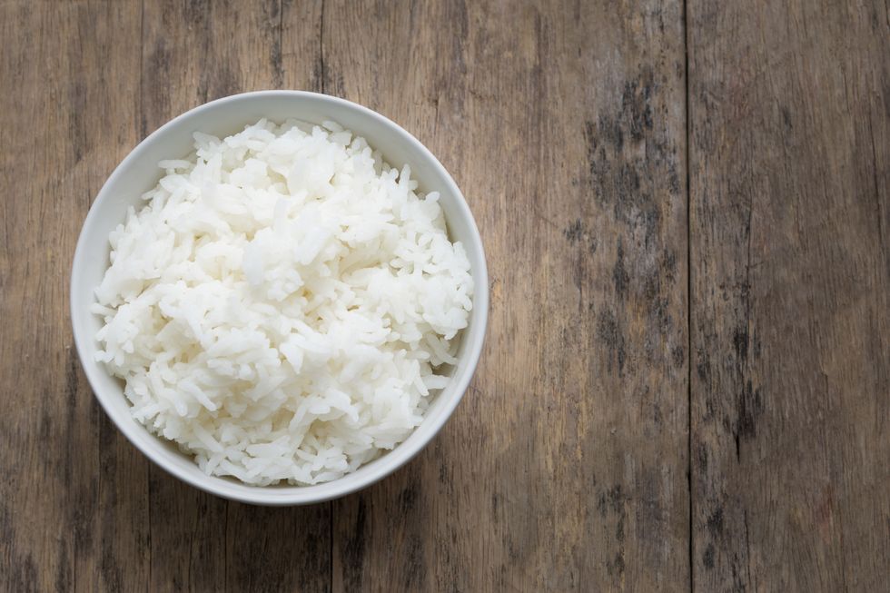 White rice in bowl on wooden table, top down