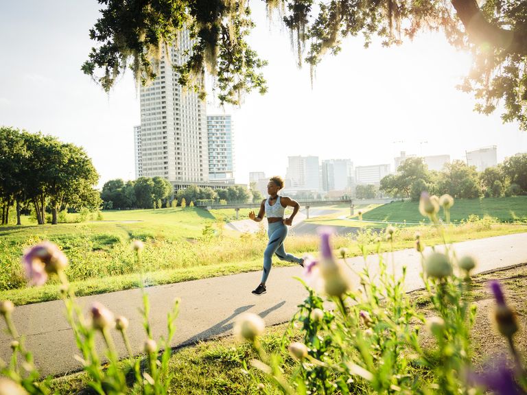 woman Klein running on path in park beyond wildflowers