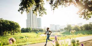 woman running on path in park beyond wildflowers
