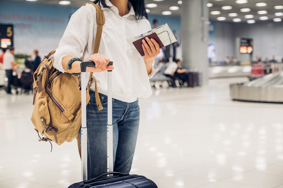 Midsection Of Woman Standing With Luggage At Airport