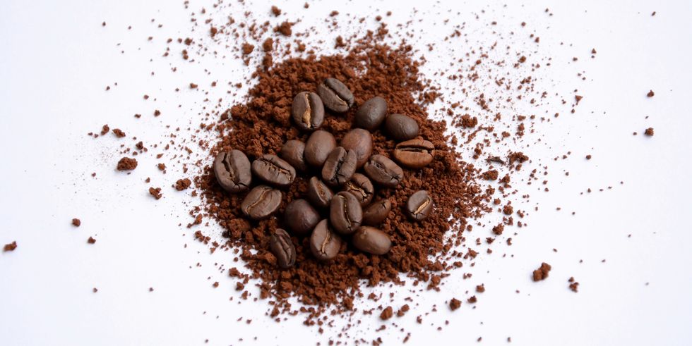 high angle view of ground coffee and beans over white background