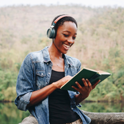 black woman reading book with nature background