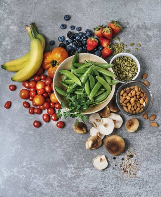 fresh vegetables, fruits, and nuts on gray background