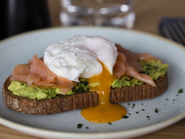weight loss breakfast rye bread with smashed avocado, smoked salmon and poached egg with yolk flow