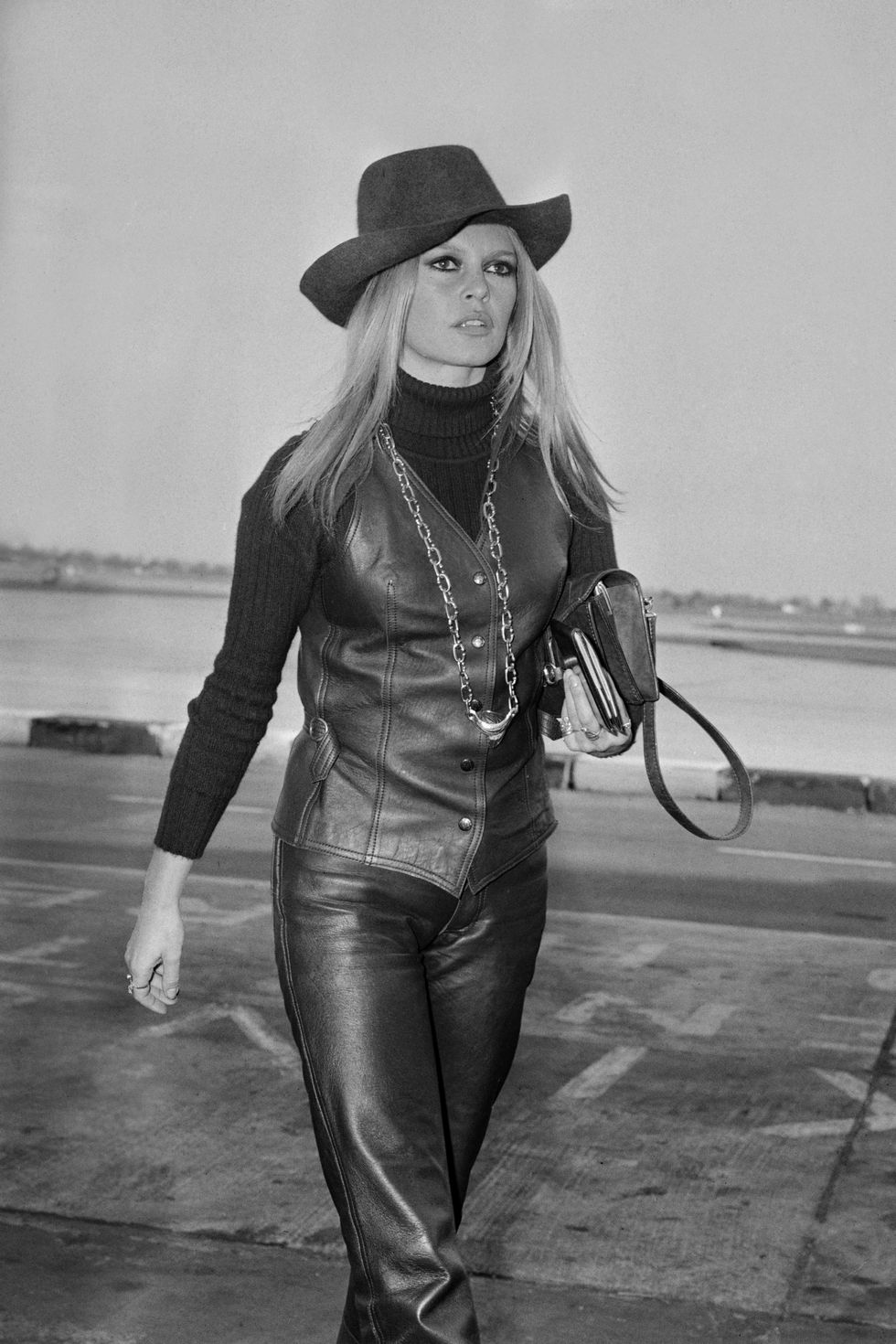 Brigitte Bardot caminando con sombrero, chaleco y pantalones de cuero