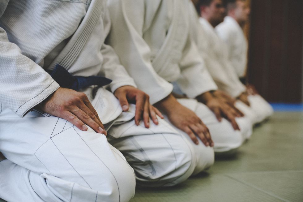 Several jiu jitsu competitors sit on a mat. 