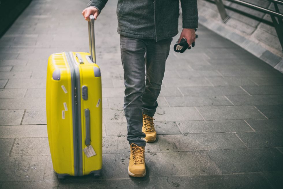 Close up of young man walking with luggage