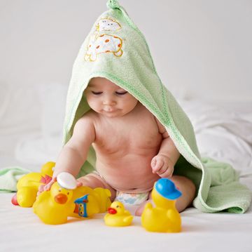 cute little baby toddler boy, playing with rubber ducks after bath in bed