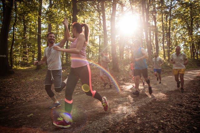 young couple running a marathon in the forest and giving high five to each other