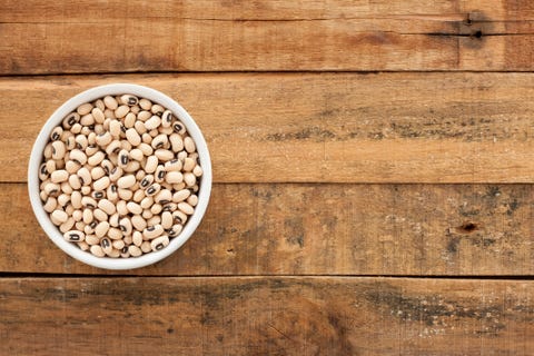 top view of white bowl full of black eyes peas over wooden table