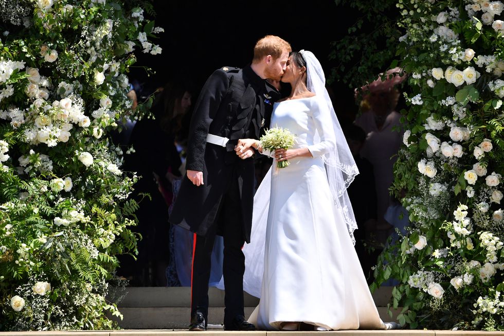 windsor, united kingdom   may 19 britain's prince harry, duke of sussex kisses his wife meghan, duchess of sussex as they leave from the west door of st george's chapel, windsor castle, in windsor on may 19, 2018 in windsor, england photo by  ben stansall   wpa poolgetty images