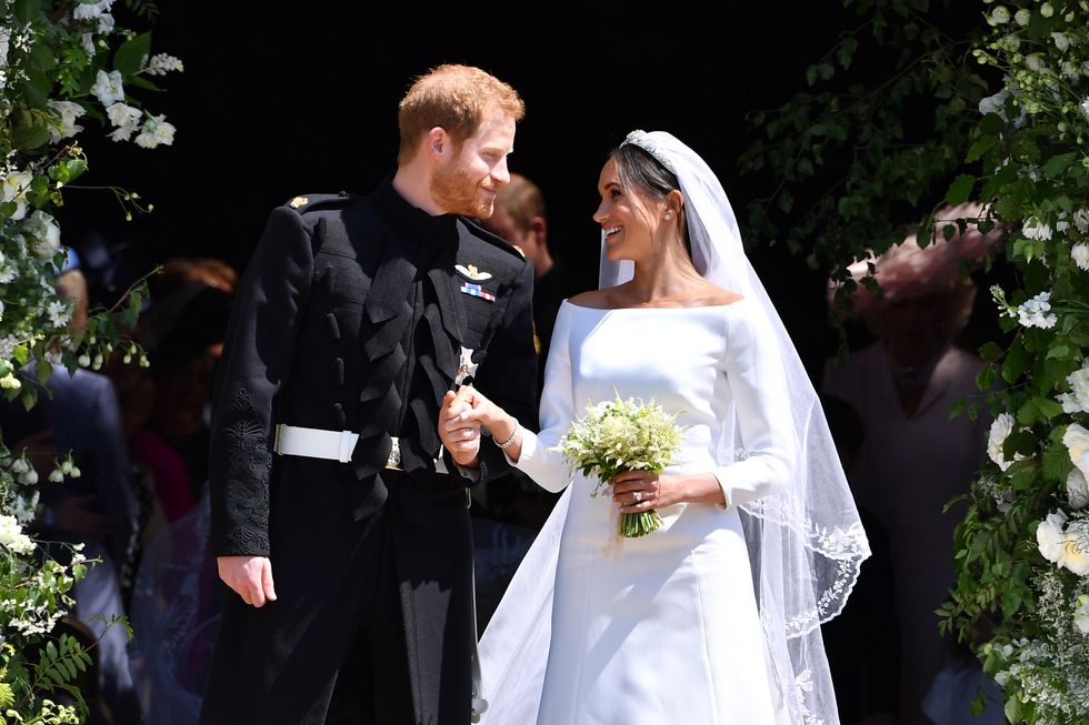 prince harry, in a black military uniform, and meghan markle, in a long sleeved white gown and veil, leave the chapel during their 2018 wedding