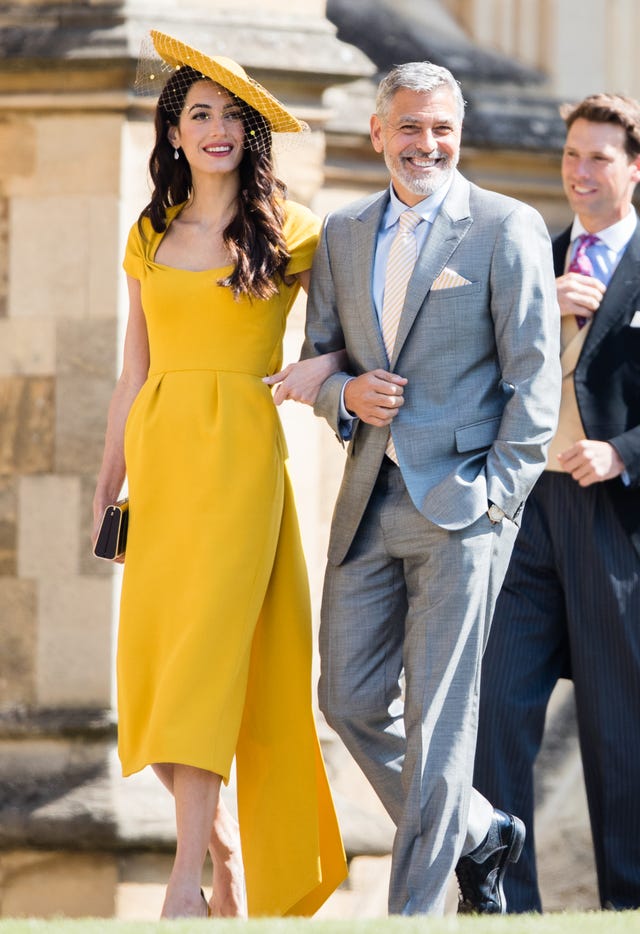 Amal Clooney en la boda de Meghan Markle con vestido amarillo de manga corta y tocado a juego