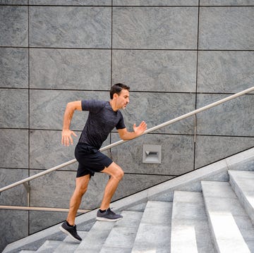 Side view of a mature man running up steps sporty man running up steps in urban setting