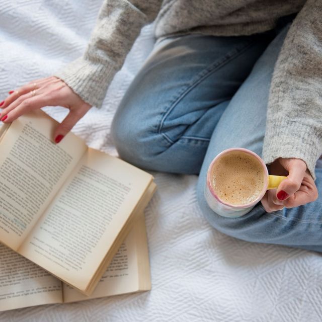 una chica leyendo con un cafe en la mano