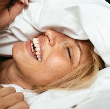 portrait of a young beautiful woman waking up among the bed sheets, with a smile on her face portrait of a young beautiful woman waking up among the bed sheets, with a smile on her face