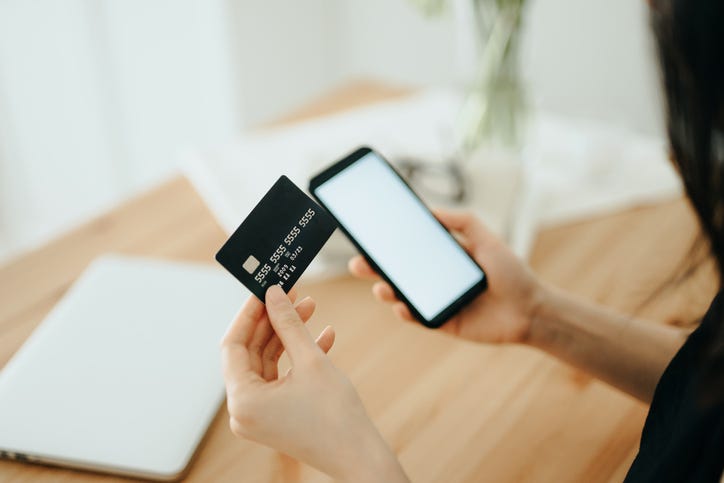 woman shopping online with smartphone and credit card on hand