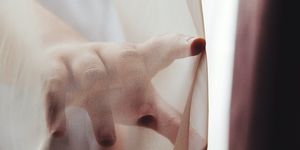 Close-Up Of Hand Touching Curtain