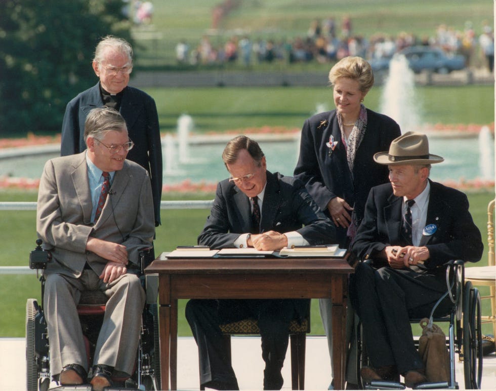 george bush signs the americans with disabilities act of 1990; standing left to right reverend harold wilkie, sandra parrino of the national council on disability; seated left to right, evan kemp, chairman of the equal employment and opportunity commission, george bush, justin dart, chairman of the s committee on the employment of people with disabilities. washington dc, usa, 26 july 1990. (photo by fotosearch/getty images).