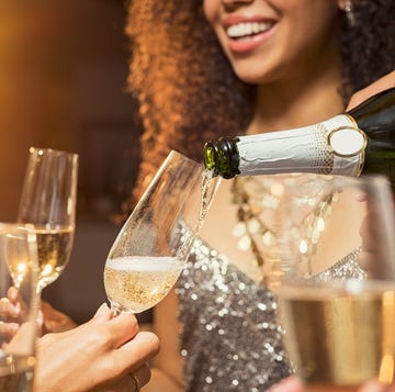 Pouring champagne at party hand pouring champagne from bottle into glasses with friends around him closeup of hand pouring champagne in flutes during new years eve party
