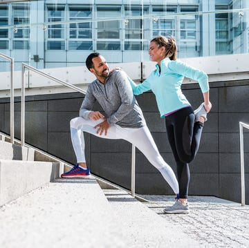 Couple doing stretching exercise on stairs in the city Two individuals stretching before a workout on outdoor steps