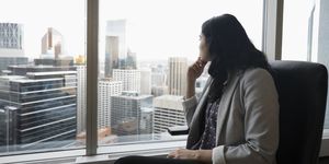 Forward looking businesswoman looking out urban office window
