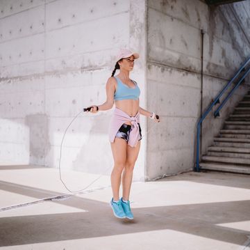 young sporty teenage girl doing sports training and working out with jump rope outdoors