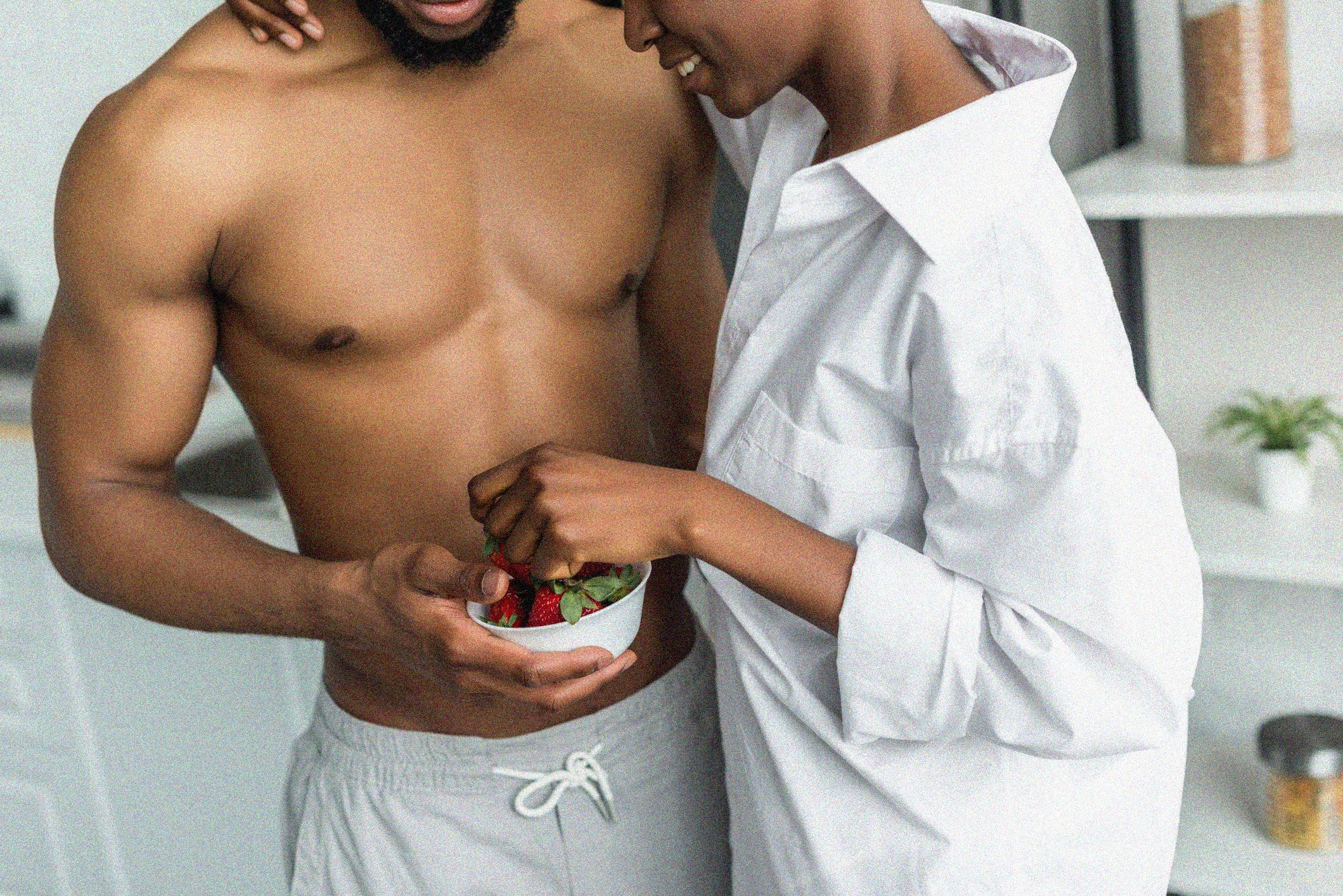 cropped image of african american couple eating strawberries at kitchen