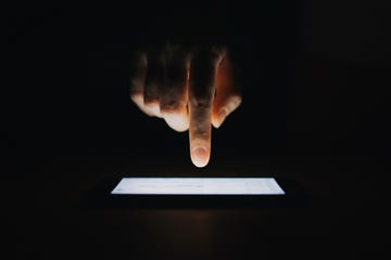 close up of womans hand checking emails on smartphone against black background