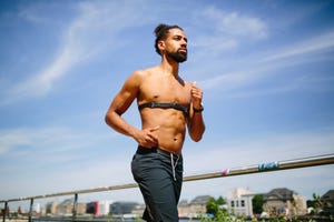 man running with heart rate monitor outdoors in the city muscular african man on morning run with a heart rate monitor strapped across his chest