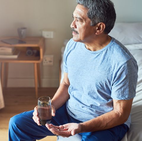 shot of a cheerful mature man seated on his bed and about to drink medication with water in the bedroom at home during the day vitamin b12 men's health