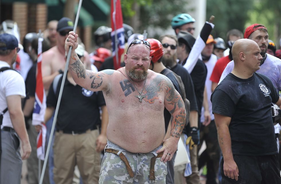 A white supremacist man is seen holding a long pipe during