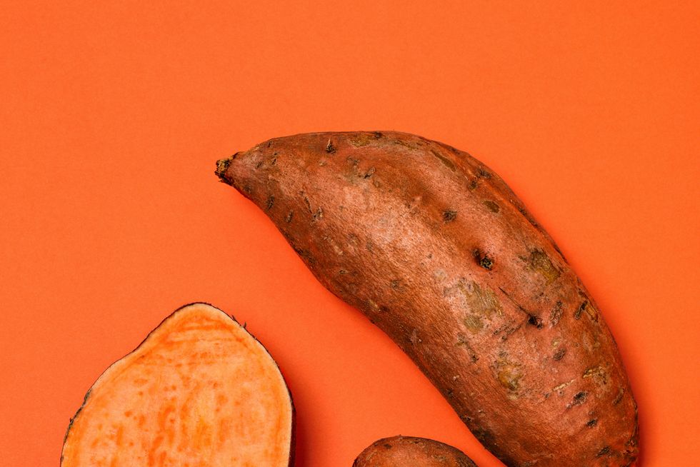 whole and halved sweet potatoes on an orange background sweet potatoes are a root vegetable rich in fiber and vitamins, and are available all year round