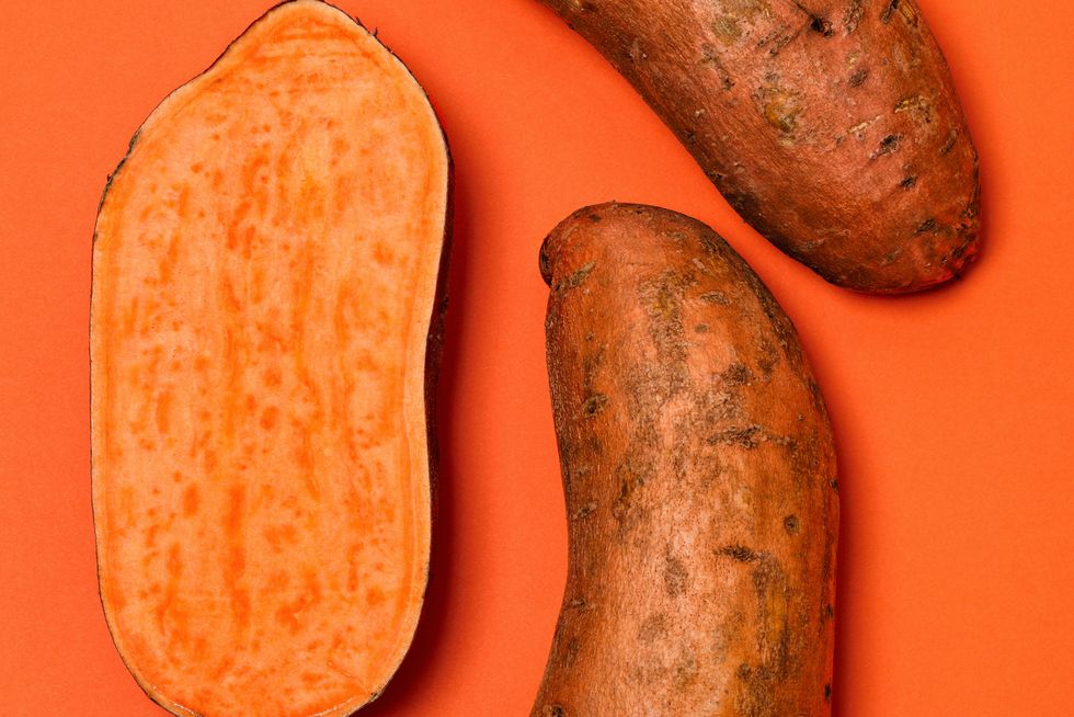 whole and halved sweet potatoes on an orange background sweet potatoes are a root vegetable rich in fiber and vitamins, and are available all year round
