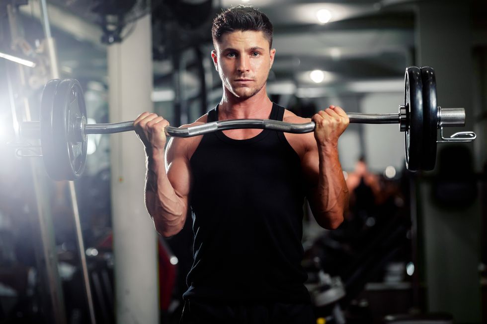 Portrait Of Man Lifting Dumbbell In Gym